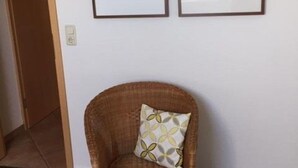 Una habitación con una silla de mimbre y un cuadro en la pared.