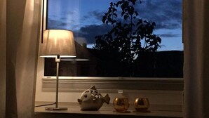 Eine Lampe, ein fischförmiger Schmuckgegenstand und zwei kleine Vasen auf einem Fensterbrett.