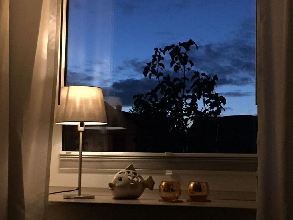 Une lampe, un objet décoratif en forme de poisson et deux petits vases sur un rebord de fenêtre.