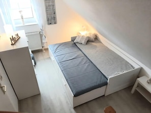 Ein kleines, modernes Schlafzimmer mit Bett, Nachttisch und einem Schreibtisch.