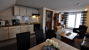 Un espace de vie compact comprenant une kitchenette, un coin repas et un téléviseur.