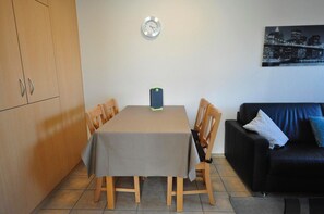 A dining area with a table, chairs, a clock, a black couch, and a cityscape painting.