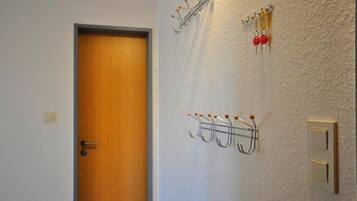 Ein Flur mit einer Holztür, einem an der Wand befestigten Kofferständer mit Haken und einem Lichtschalter.