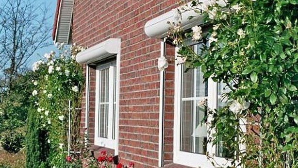 Une maison en briques avec des encadrements de fenêtres blancs et un petit porche.
