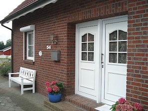 Un edificio de ladrillo con una puerta blanca y un banco blanco en el exterior.