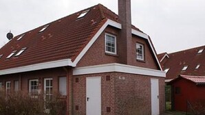 A red brick building with a pitched roof, a chimney, and two white doors.