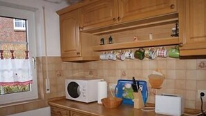 A kitchen with wooden cabinets, a microwave, a toaster, and various kitchen utensils on the counter.