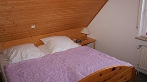 A single bed with a wooden headboard and a nightstand with a lamp.