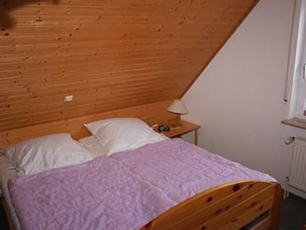 A single bed with a wooden headboard and a nightstand with a lamp.
