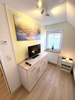 Eine kleine Küche mit Fernseher, einem Gemälde und einem Fenster.