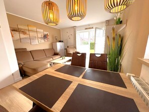 A modern living room with a sofa, a dining table with placemats, and two hanging pendant lights.