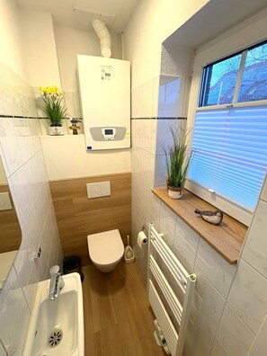 Un baño pequeño con inodoro, lavabo y radiador.