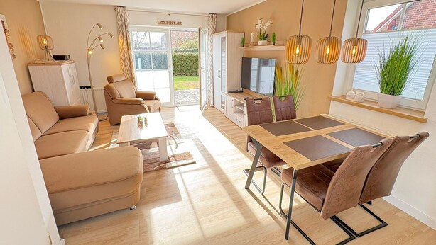 Una sala de estar moderna con un sofá, una mesa de comedor con sillas, un televisor y una zona de cocina.