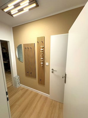 A hallway with a wooden floor, a white door, and a wall-mounted mirror.