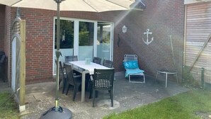Een terras met een tafel en stoelen, een klein trampoline en een bakstenen muur.