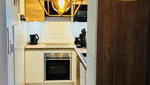 Een moderne keuken met een ingebouwde oven, een koffiezetapparaat en hangende lampen.