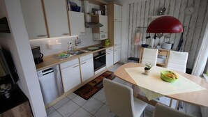 Eine moderne Küche mit weißen Schränken, einem eingebauten Backofen und einer roten Pendelleuchte.