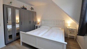 Un dormitorio con cama, dos mesitas de noche, un armario y un espejo.