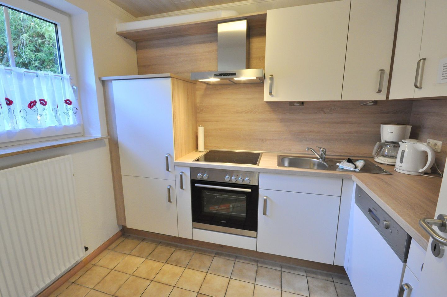 A compact kitchen with a refrigerator, oven, sink, and a coffee maker.