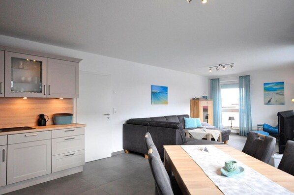 A modern kitchen with grey cabinets and a dining area with a wooden table and chairs.