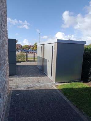 A paved pathway leading to a gated area with industrial-style buildings. - Vacation w. Int Seeburger Winkel 5 OG - Holiday apartment Int Seeburger Winkel 5 OG (Wittmund)