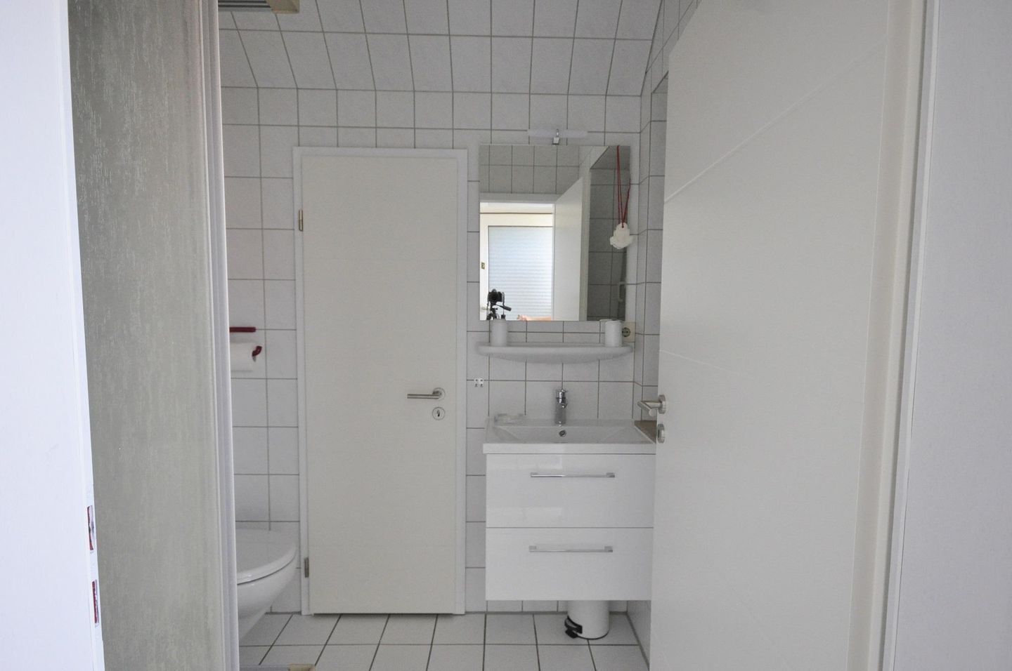 A bathroom with a toilet, sink, and mirror.