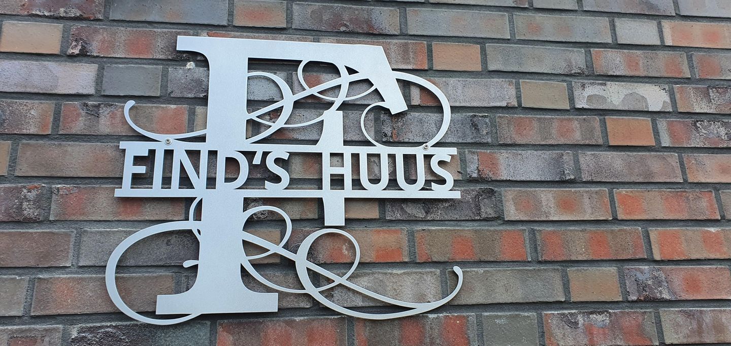 A metal sign with the text 'FIND'S HUIS' on a brick wall.