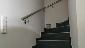 A staircase with a handrail, a light switch, and a small wall-mounted object. - Vacation home Krabbenpadd 9 "Find's Huus" - Holiday home "Find's Huus" Krabbenpadd 9 (Wittmund)