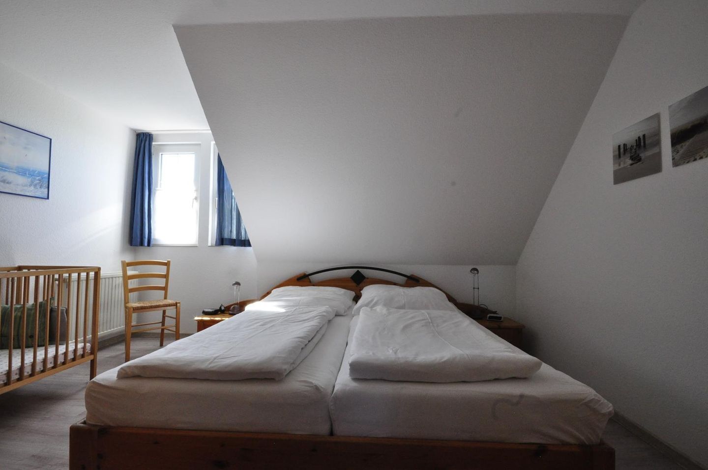 Een eenvoudige, goed verlichte kamer met een enkel bed, een stoel en een wieg.