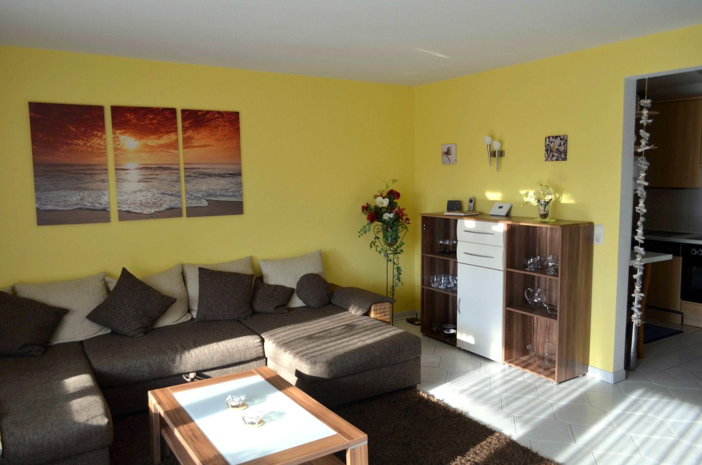 Ein Wohnzimmer mit einer Couch, einem Couchtisch und einer Vitrine mit Gläsern.