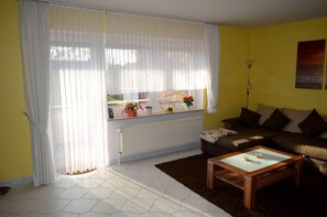 Een woonkamer met een bank, een salontafel en een raam met gordijnen.