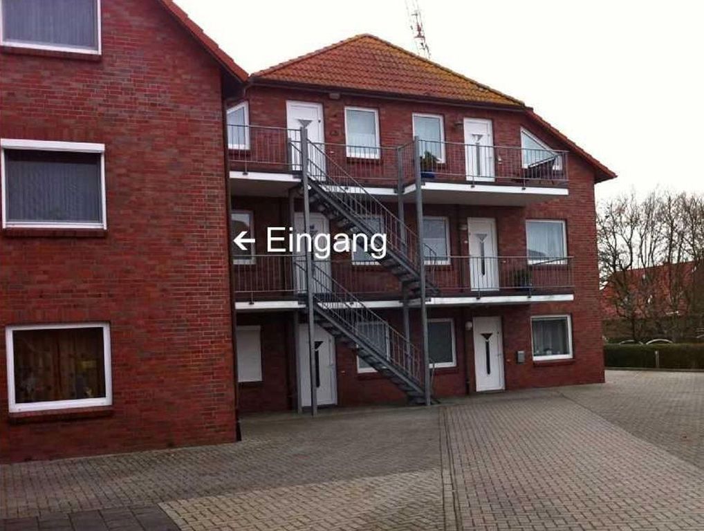A red brick building with a staircase leading to a balcony.