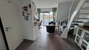 Un intérieur moderne comprenant une cuisine, un coin repas et un escalier.