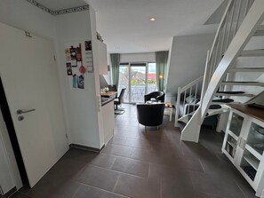 A modern interior with a kitchen, dining area, and a staircase.