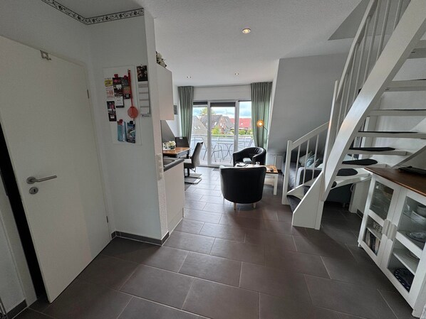 A modern interior with a kitchen, dining area, and a staircase.