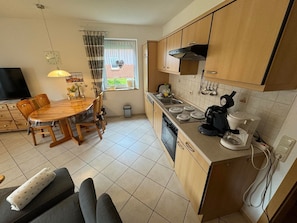 Una cocina funcional con armarios de madera, una mesa de comedor y una cafetera.
