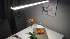 Une table à manger dressée avec des assiettes, des couverts, un verre, une fleur et un petit vase.