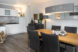 Eine moderne Küche mit weißen Schränken, einem Holztisch mit schwarzen Stühlen und einem Bild an der Wand.
