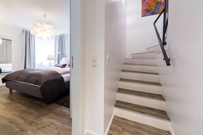 A modern bedroom with a bed, a staircase, and a view of the outside. - Domizil am Möwenberg 14 - Modern 3-room apartment with 2 bedrooms and 2 bathrooms (Scharbeutz)