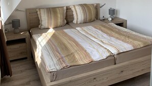 A bedroom with a bed, two nightstands, a lamp, and a wall with 'Trauland' and 'Love' decorations. - Vacation cottage Mittelweg 41a (Wittmund)