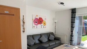 A living room with a sofa, a coffee table, and a painting on the wall. - Vacation cottage Mittelweg 41a (Wittmund)