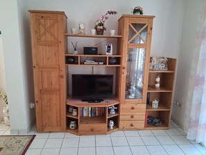 A wooden entertainment unit with a television, shelves, and storage compartments.