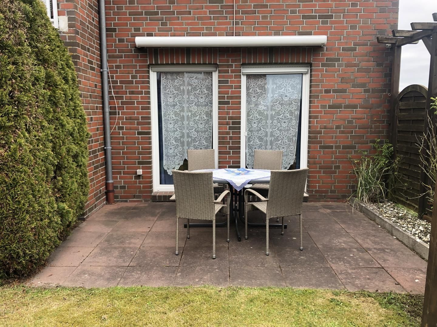 Ein Backsteinhaus mit einer Terrasse, komplett mit Tisch und Stühlen.