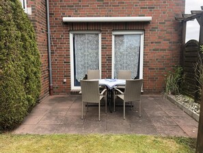 A brick house with a patio area featuring a table and chairs.