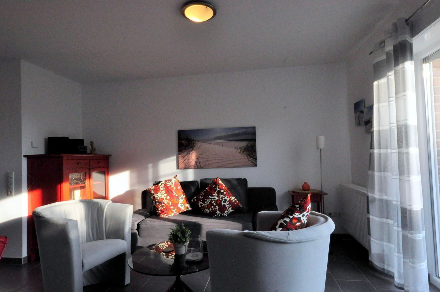 A living room with a sofa, two armchairs, a coffee table, and a painting on the wall.