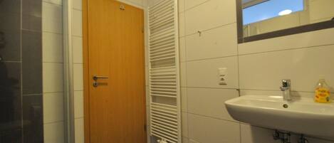 A bathroom with a wooden door, a white sink, and a mirror above it.
