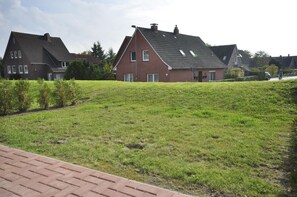 A residential area with houses, a grassy hill, and a paved walkway. - Residence Carolinensiel Mühlenstraße 28 Whg. 3 - Residence Carolinensiel 1 (Wittmund)