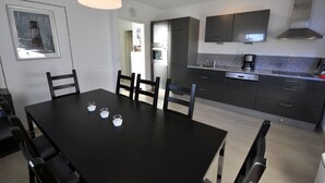 A modern kitchen with dark cabinetry, a black dining table, and a pendant light.