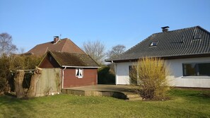 A house with a sloped roof, a fenced yard, and a small shed. - "Up de Ring 13" Vacation Rental (Wittmund)