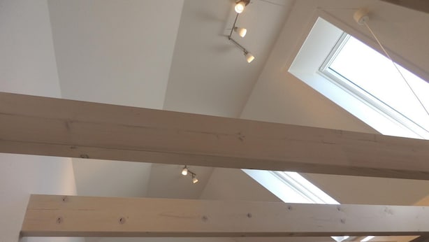 Een hoge plafond met dakramen en zichtbare houten balken.